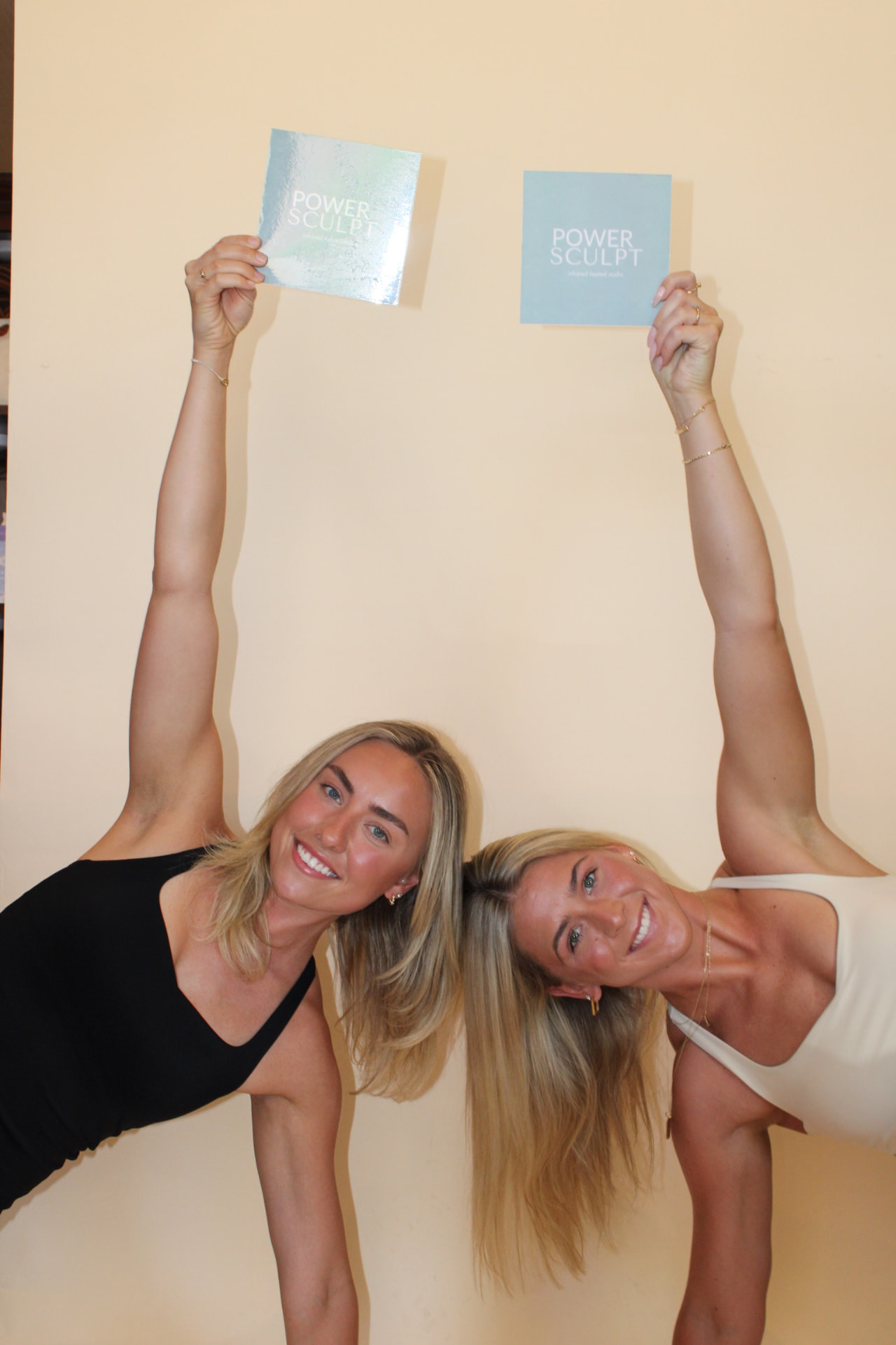 Two instructors holding Power Sculpt cards overhead
