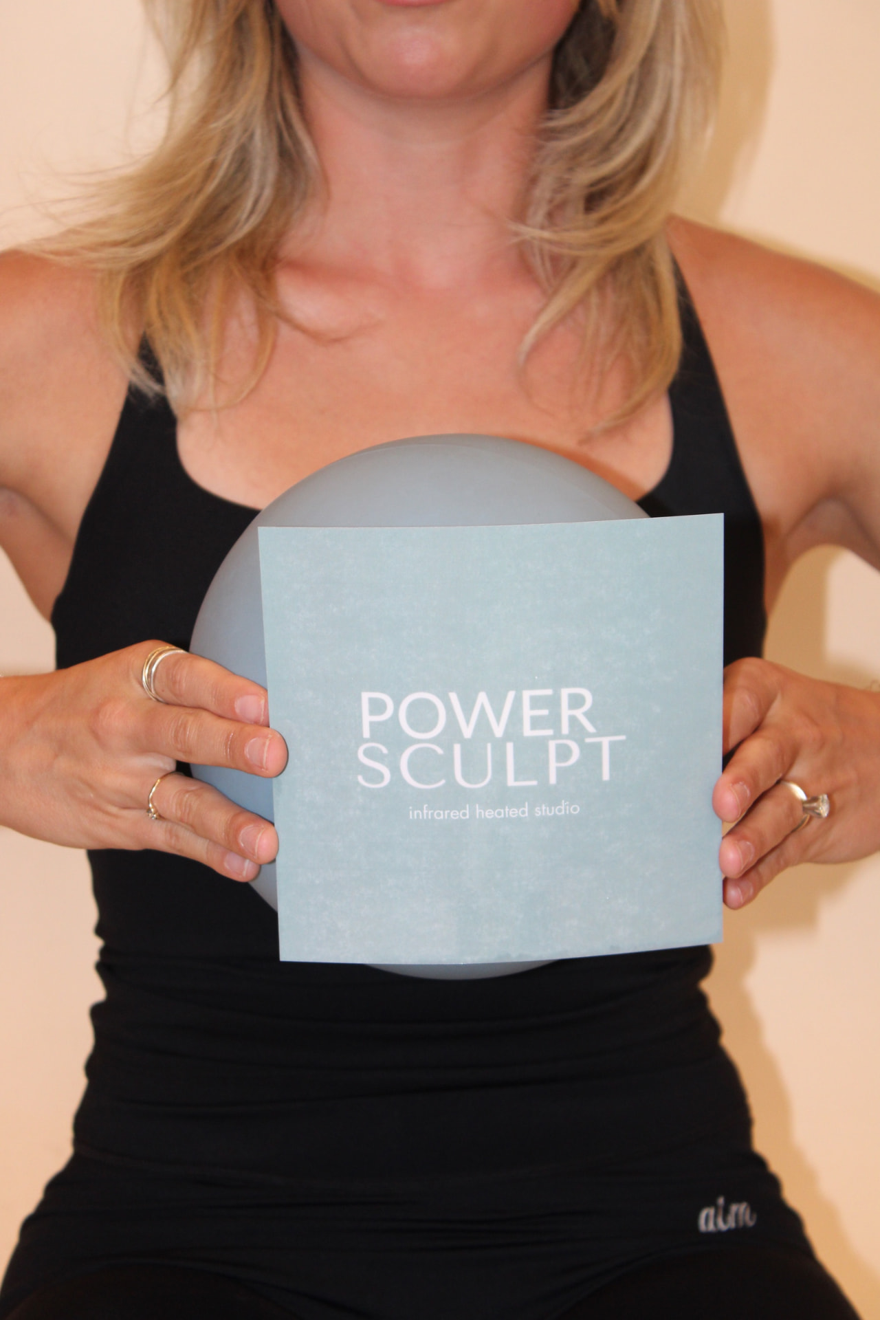 Instructor holding a Power Sculpt card and pilates ball